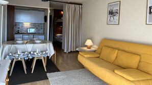 A compact living space with a dining area, a sofa, and a kitchen.