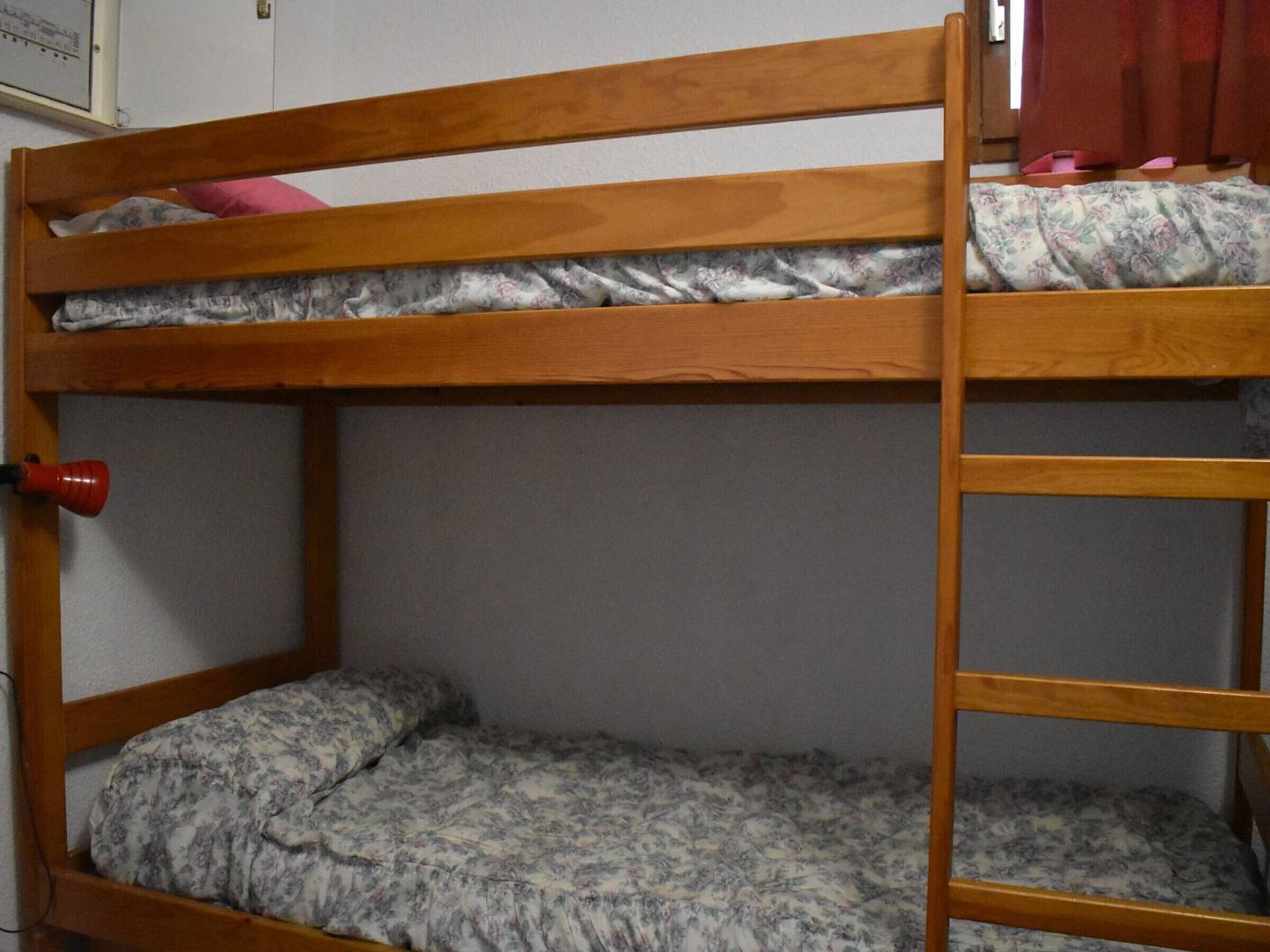 Ein Etagenbett mit einem roten Wecker auf der linken Seite.