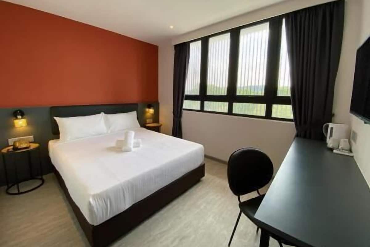 Una habitación de hotel con cama, mesitas de noche, un escritorio y una silla.