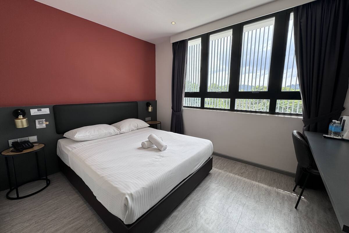 Habitación de hotel con una cama grande, un escritorio y una ventana con cortinas.