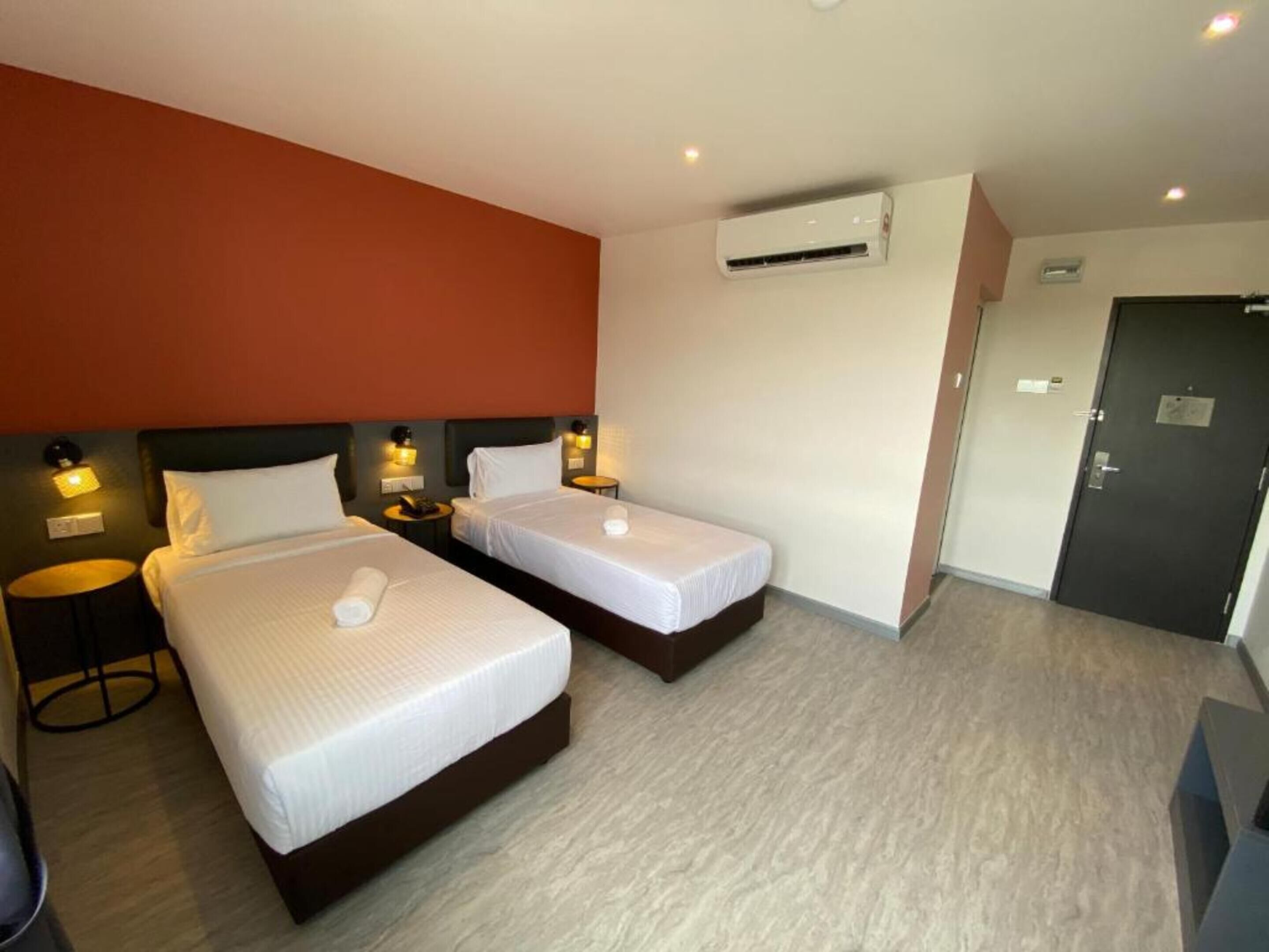 Habitación de hotel con dos camas, aire acondicionado de pared y una puerta.