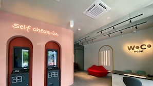 Un quiosco de auto-check-in, una recepción y un cartel del hotel WOC.