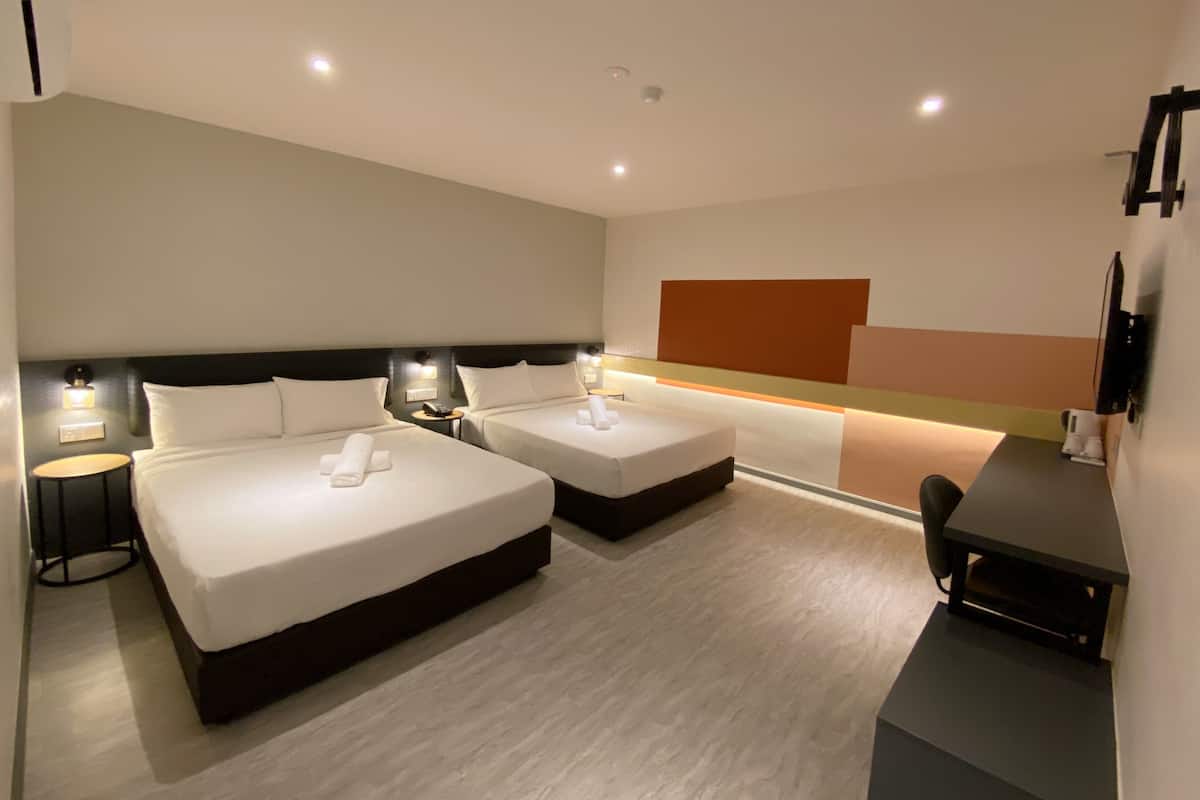 Habitación de hotel con dos camas, un escritorio y una televisión.