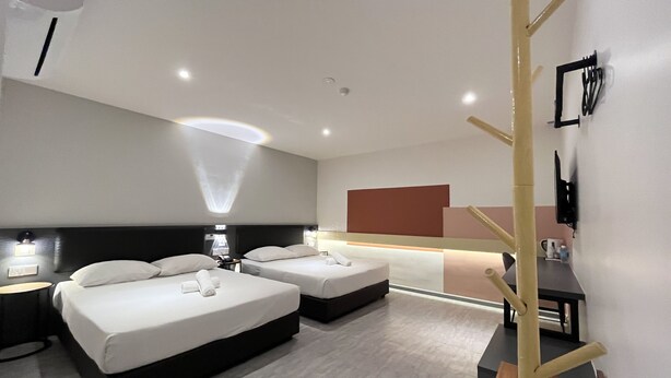Una habitación de hotel moderna con dos camas, una mesita de noche, un televisor y un estante en la pared.