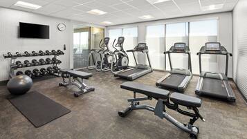 A gym with treadmills, elliptical machines, dumbbells, and a stationary bike.