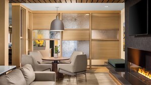 A modern living room with a sofa, chairs, a round table, a fireplace, and a TV mounted on the wall. - Fairfield Inn & Suites by Marriott Duluth (Duluth)