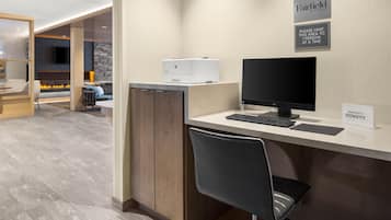 A hotel reception desk with a computer, a printer, and a sign indicating a limit of one person at a time.