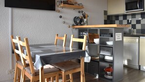 Una cocina compacta con una mesa de comedor, sillas y un microondas.