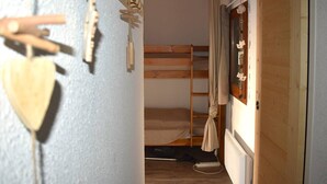 Habitación con literas, una escalera de madera, una ventana con cortinas y un radiador.