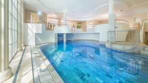 An indoor swimming pool with a clear blue water, surrounded by a tiled floor and walls, and a staircase leading to an upper level. - Double room Comfort - ROEWERS Privathotel & Spa (Sellin)