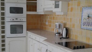 Una cucina con mobili bianchi, un forno a microonde, un piano cottura e una macchina per il caffè.