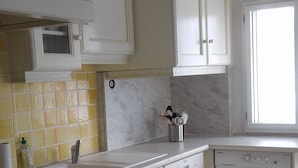 Una cucina con mobili bianchi, un forno a microonde, un lavandino e una lavatrice.
