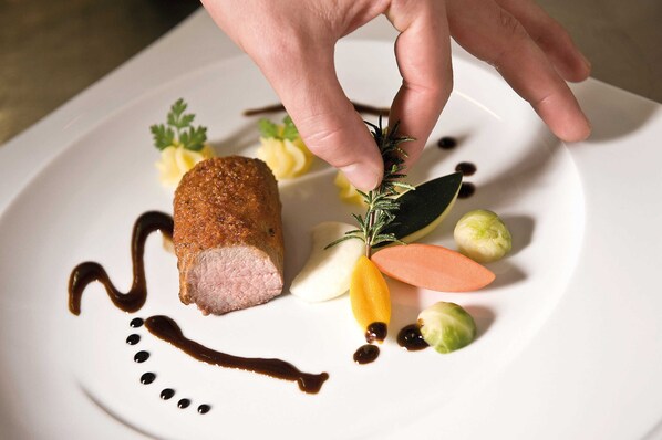 A plated dish with a piece of meat, vegetables, and sauce.