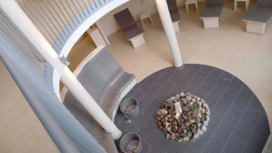Ein mehrgeschossiges Atrium mit einer zentralen Sitzgruppe, einschließlich einer Feuerstelle, die von Steinen umgeben ist.