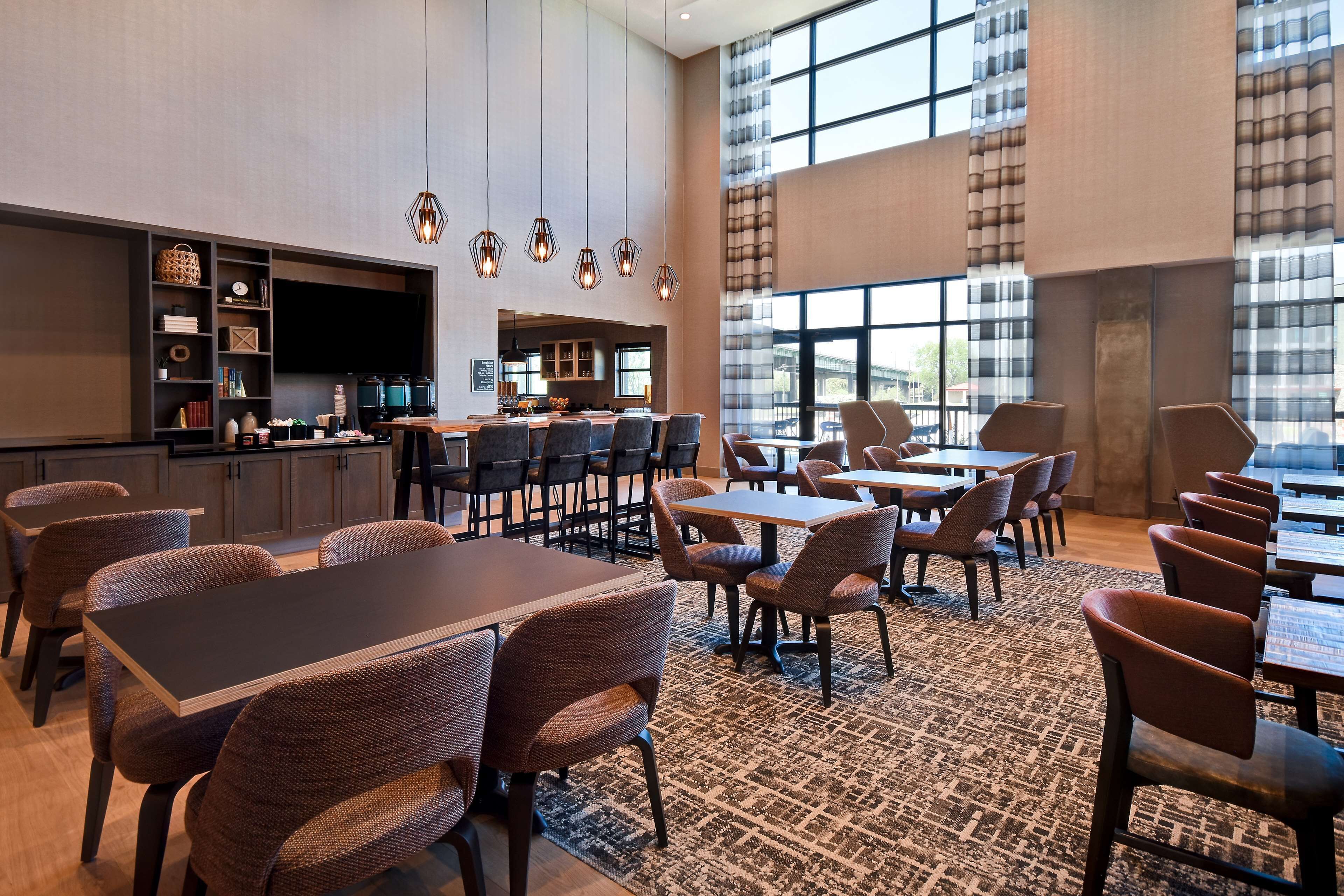 Un moderno vestíbulo de hotel con área de bar, asientos y grandes ventanales con vistas.