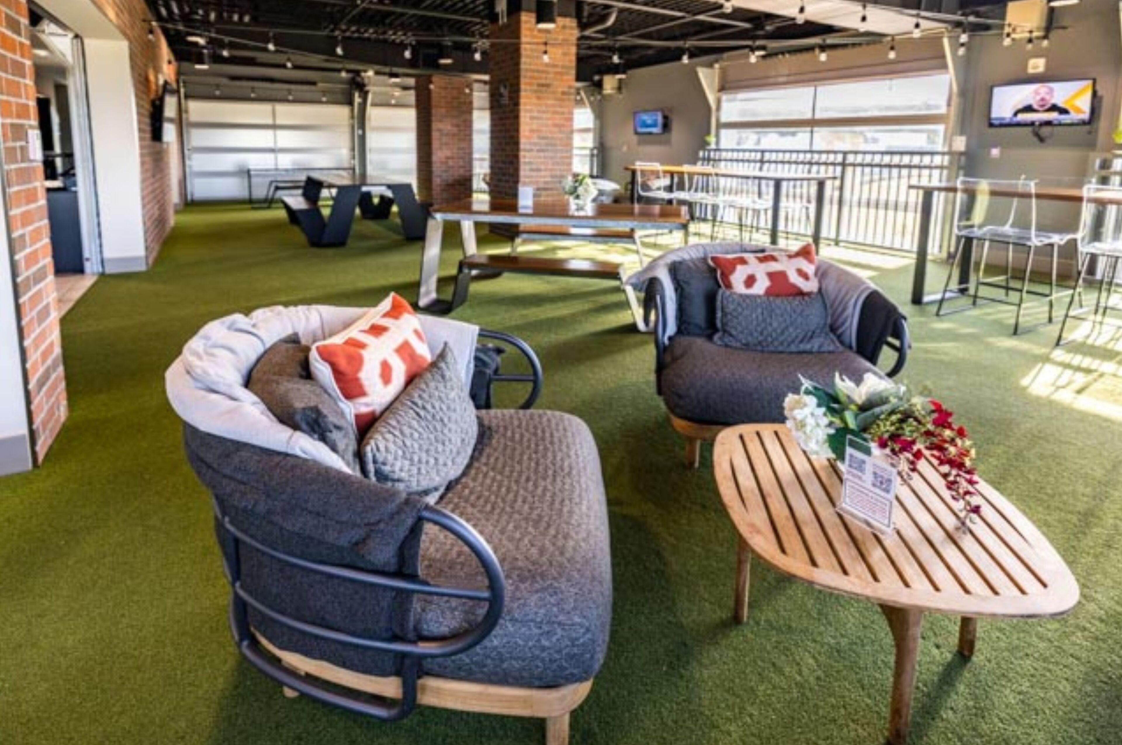 A modern lounge area with two sofas, a wooden coffee table, and a brick wall.