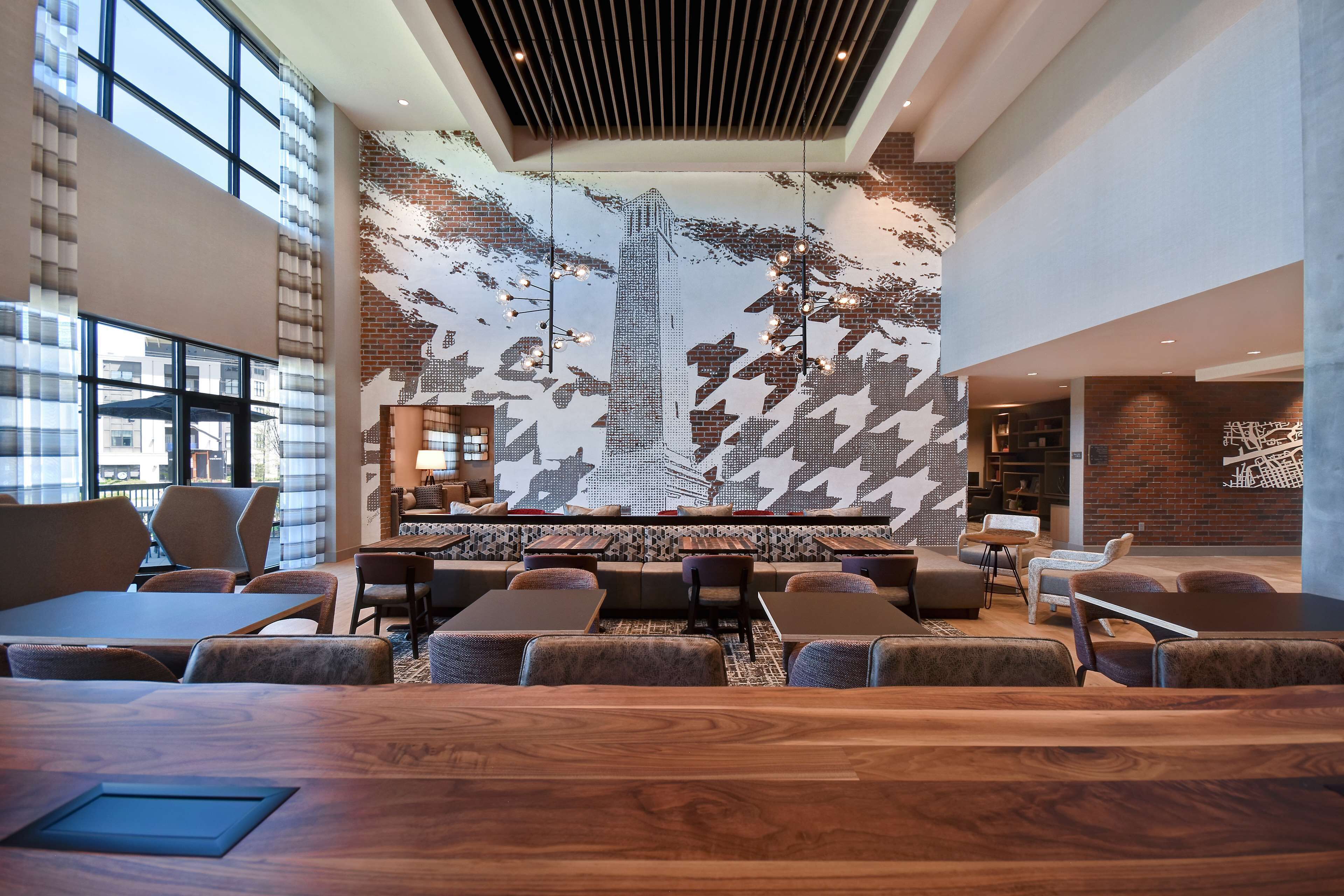 Un área de estar moderna con un mural grande de un paisaje urbano, asientos cómodos y un mostrador de recepción de madera.