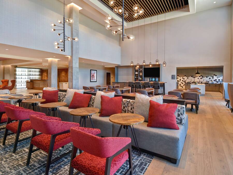 A spacious lobby with multiple seating areas, including sofas and chairs, and a bar area.