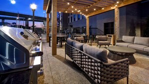 An outdoor patio area with a grill, seating, and string lights. - Homewood Suites by Hilton Tuscaloosa Downtown (Tuscaloosa)
