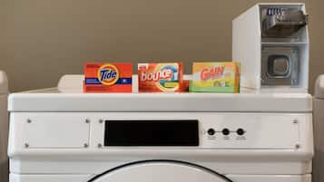 A front-loading washing machine with Tide, Bounce, and Gain detergent boxes on top.
