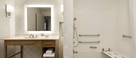 Un bagno moderno con uno specchio grande, una vasca da bagno e una doccia dotata di maniglioni.