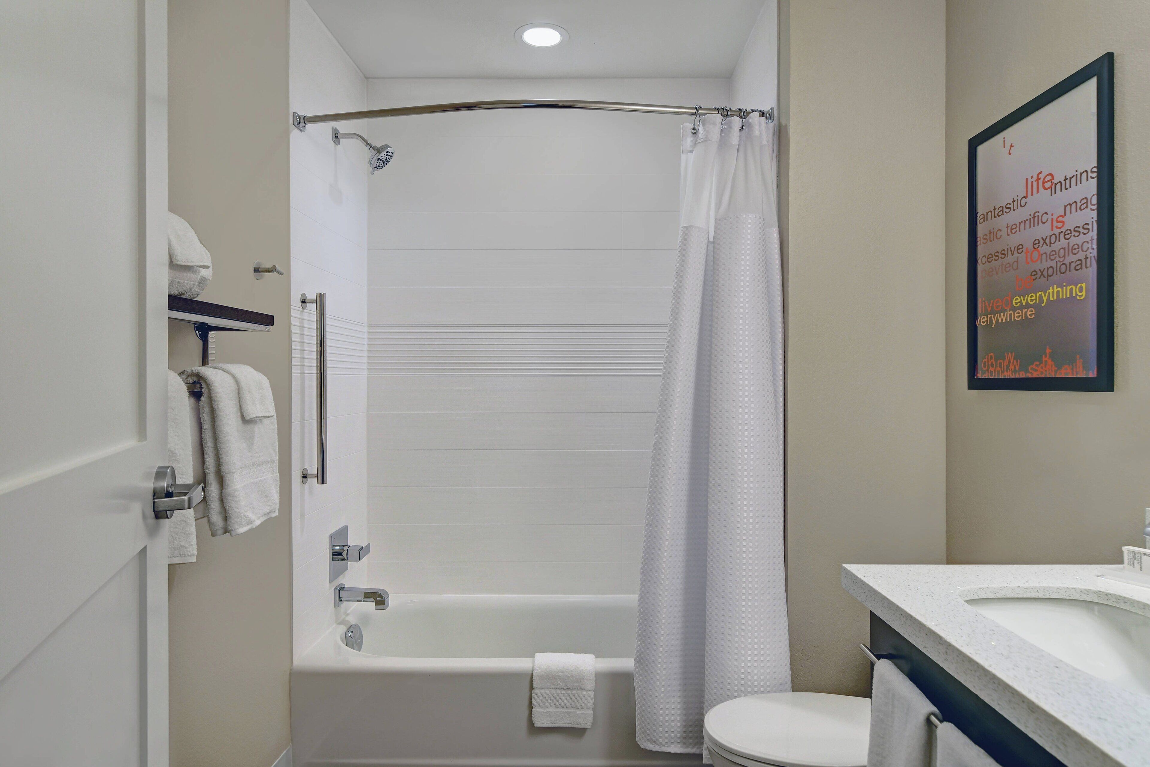 A bathroom with a bathtub, toilet, and a shower curtain. There are towels hanging on the wall and a sink with a mirror.