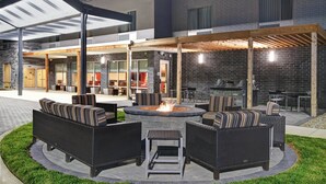 An outdoor patio area with wicker furniture, a fire pit, and a covered seating area. - TownePlace Suites by Marriott Lima (Lima)