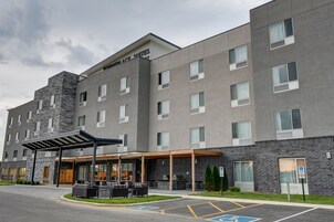 Un hotel moderno con fachada de piedra, zona de estar exterior y señal de estacionamiento para discapacitados.