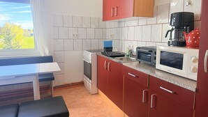Una cucina compatta con fornello, forno a microonde e macchina del caffè.