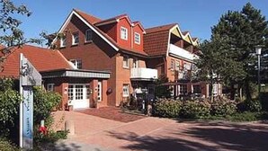 Een gebouw van rode baksteen met een centrale ingang, meerdere ramen en een heldere lucht.