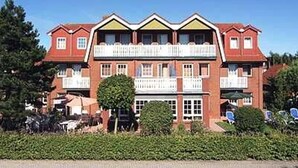 A multi-story hotel with a symmetrical facade, balconies, and a well-maintained garden area. - Double room non-smoking category I - Double room in the Hotel-Pension (Esens)