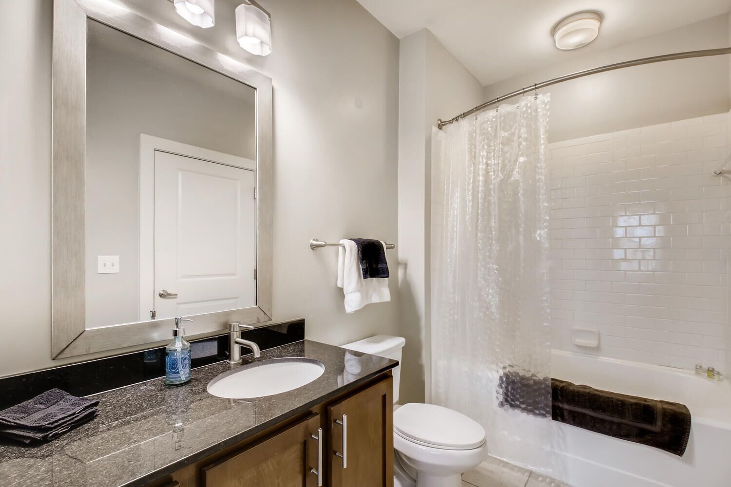 A bathroom with two sinks, a toilet, a shower with a glass door, and a large mirror.