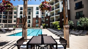 A poolside area with a rectangular pool, lounge chairs, and a pergola with hanging flower baskets. - Downtown in the Gulch - Spacious 2bed/2bath - Walk to Broadway! (Nashville)