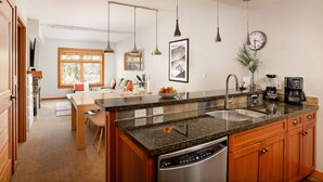 A modern kitchen with granite countertops, stainless steel appliances, and wooden cabinets. - Incredible Snowmass Condo by Gondola! Walk to Dining & Shops. A/C, Hot Tubs, Balcony, W/D, Parking! (Snowmass Village)