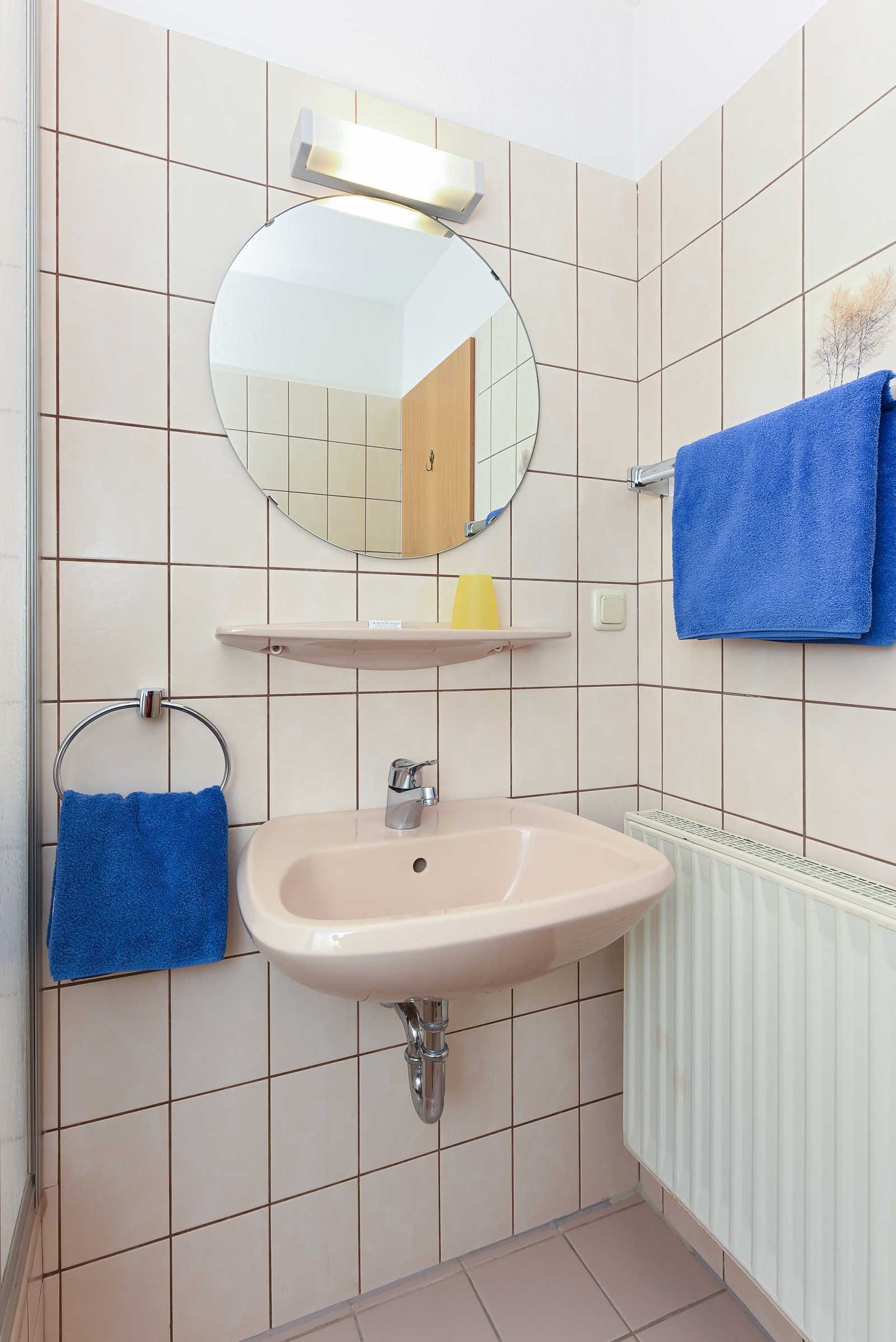 A bathroom with a sink, mirror, towel rack, and a towel hanging on the wall.