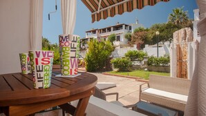 Un patio con mesa, sillas y vistas a una colina con edificios.