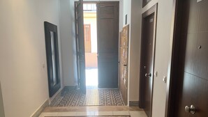 Un corridoio con piastrelle decorate, una porta in legno e una porta con un cartello sopra.