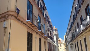 Un vicolo stretto fiancheggiato da edifici a più piani, con balconi e un cielo azzurro intenso.
