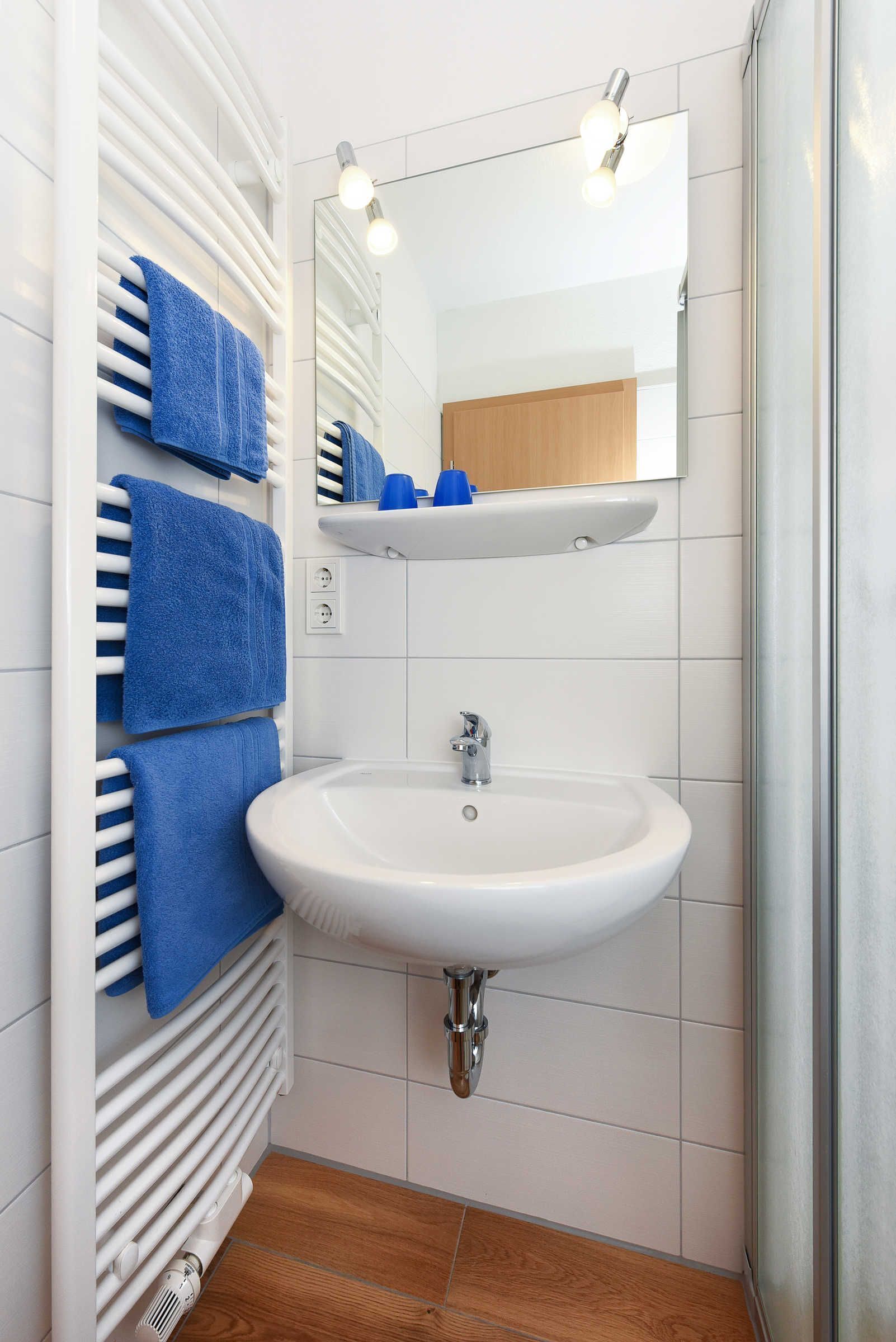 Ein Badezimmer mit einem weißen Waschbecken, einem Spiegel und einem Handtuchhalter mit blauen Handtüchern.