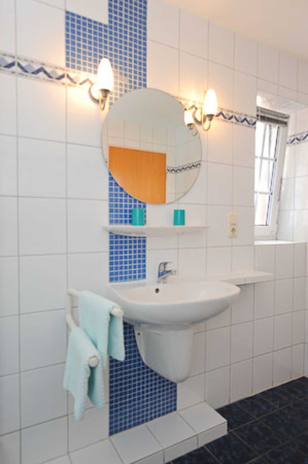 Ein Badezimmer mit Waschbecken, Spiegel und blauen Fliesen.