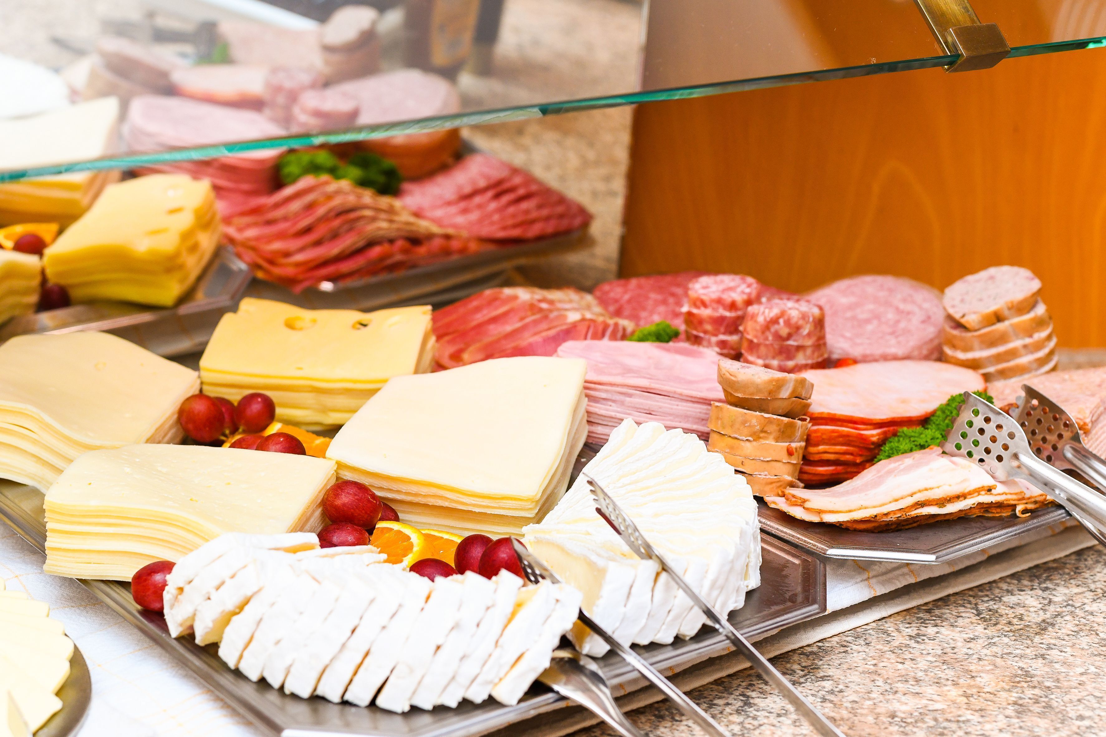 A variety of cheeses, meats, and fruits on a buffet table.