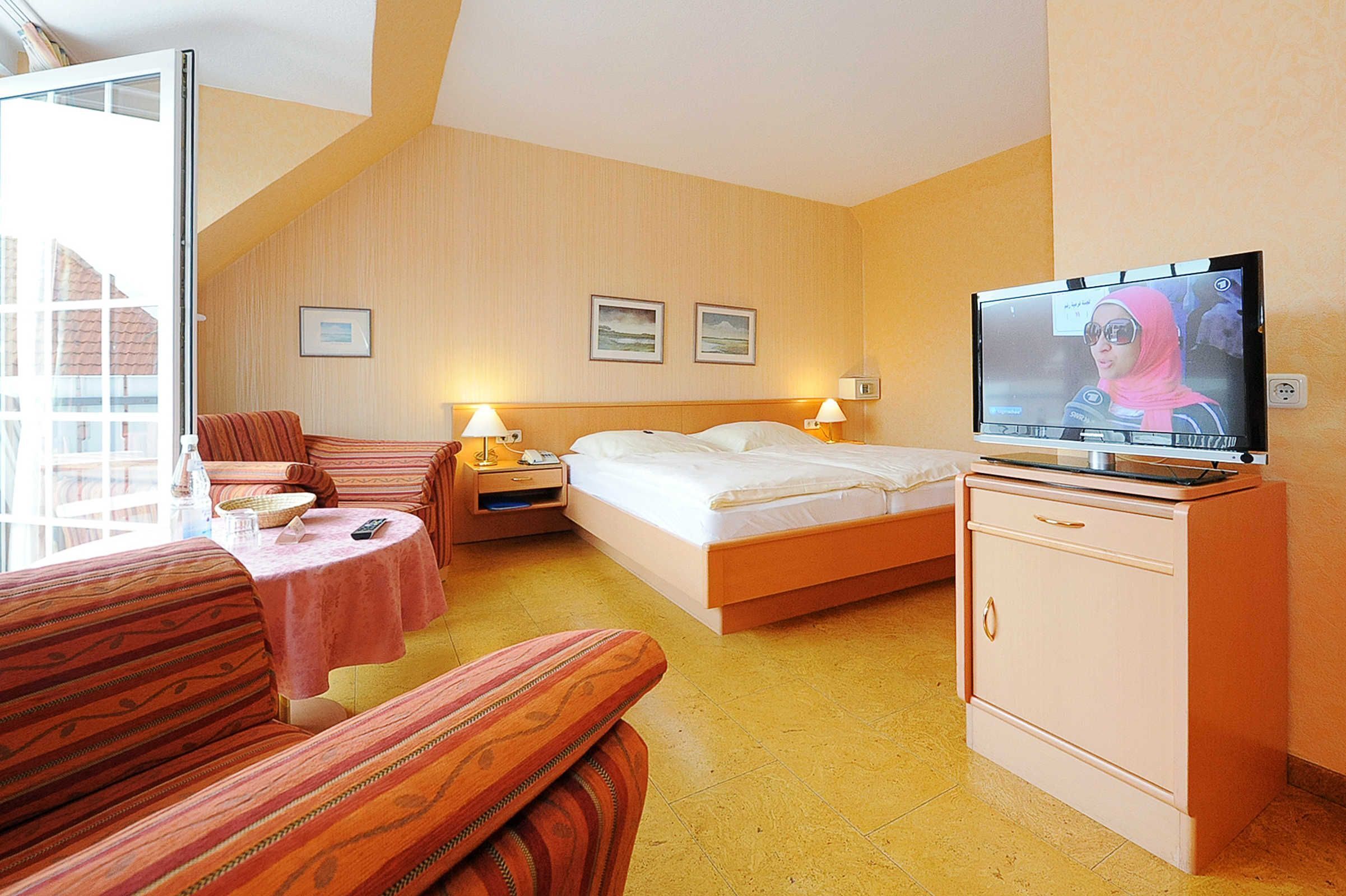 Ein Hotelzimmer mit Bett, Fernseher, Sofa, kleinem Tisch und Schrank.