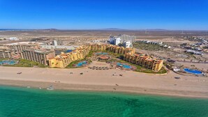 A resort with multiple hotel buildings, a beach, and a pool area.