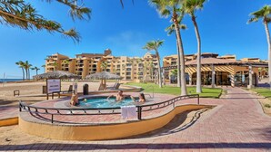 A resort with a swimming pool, palm trees, and a beach.
