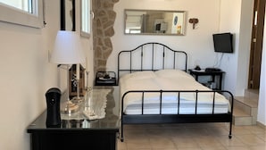 Een slaapkamer met een bed, nachtkastjes, een kaptafel, een spiegel, een airconditioner en een televisie.