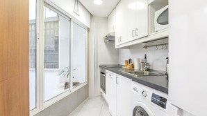 Cocina compacta con lavadora, lavamanos y armarios.