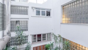 Un edificio de varios pisos con amplios ventanales, algunos con rejas, y una escalera central.