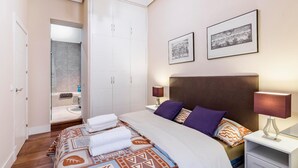 Une chambre d’hôtel comprenant un lit, des tables de chevet, une armoire et deux tableaux encadrés accrochés au mur.