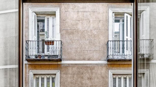 Un balcon orné de plantes en pot, un sol carrelé et un mur en pierre.