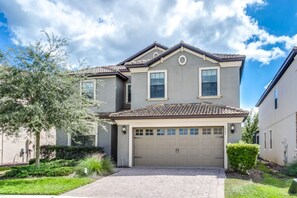 A two-story house with a garage, a tiled roof, and a well-maintained lawn. - Imagine You and Your Family Renting This 5 Star Villa on Champions Gate Resort, Orlando Villa 3611 (Davenport)